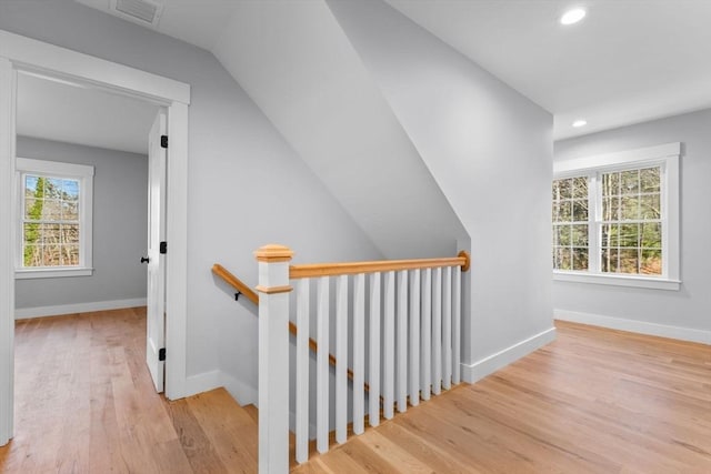 staircase featuring hardwood / wood-style floors, vaulted ceiling, and a wealth of natural light