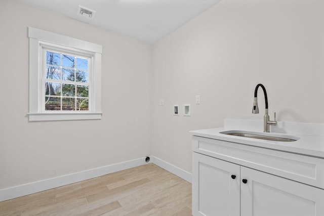 laundry area featuring cabinets, washer hookup, light hardwood / wood-style flooring, and sink