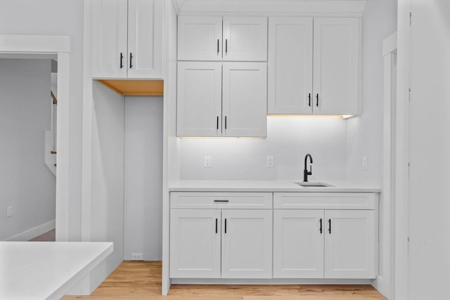 kitchen featuring light hardwood / wood-style floors, white cabinetry, and sink