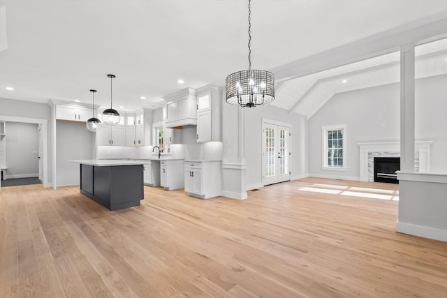 kitchen with decorative light fixtures, a notable chandelier, white cabinets, vaulted ceiling with beams, and light hardwood / wood-style floors