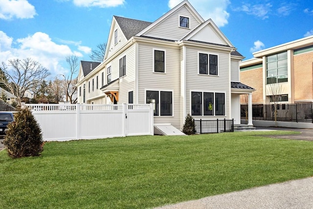 rear view of house featuring a lawn and a fenced backyard