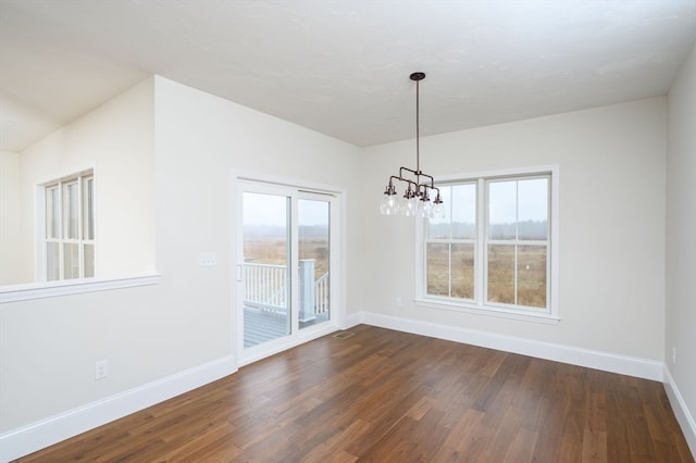 unfurnished dining area featuring an inviting chandelier and dark hardwood / wood-style flooring