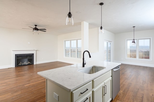 kitchen with light stone counters, dishwasher, sink, and a healthy amount of sunlight