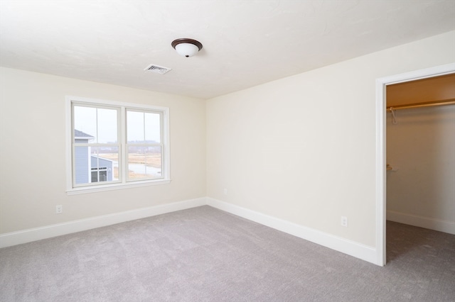 unfurnished bedroom featuring light colored carpet, a closet, and a spacious closet