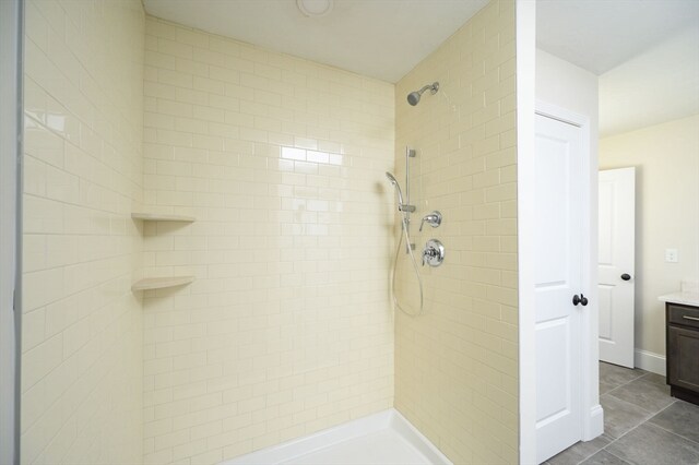 bathroom with vanity, a tile shower, and tile patterned floors