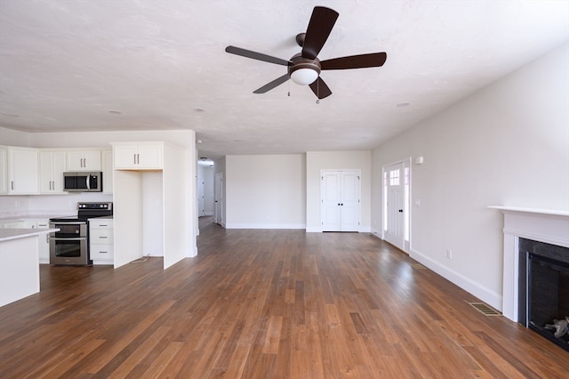 unfurnished living room featuring ceiling fan and dark wood-type flooring