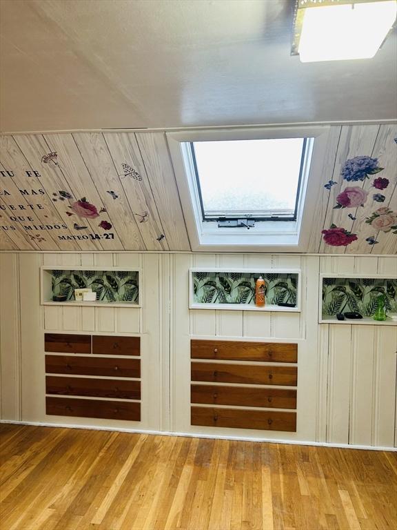 interior space featuring hardwood / wood-style floors, a skylight, wood ceiling, and wooden walls