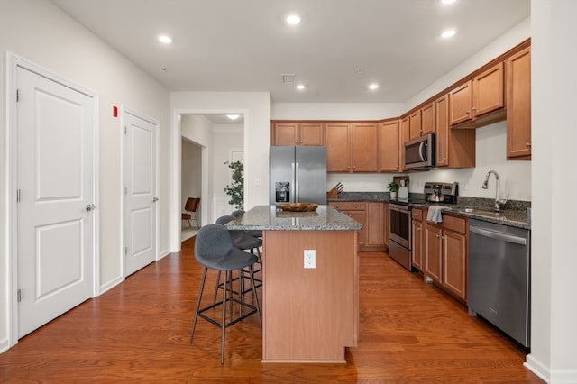 kitchen featuring dark stone countertops, a kitchen island, dark hardwood / wood-style flooring, and stainless steel appliances