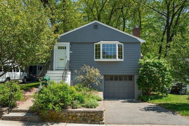 view of front of home featuring an attached garage, entry steps, a chimney, and driveway