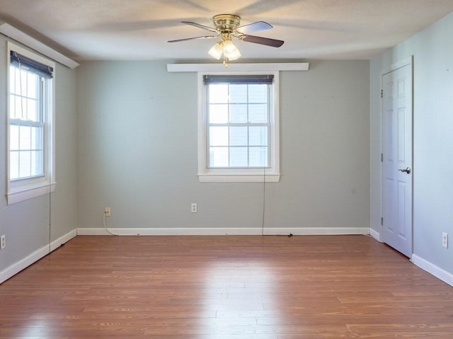 unfurnished room featuring ceiling fan, wood-type flooring, and a wealth of natural light