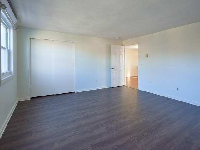 unfurnished bedroom with a closet and dark hardwood / wood-style flooring