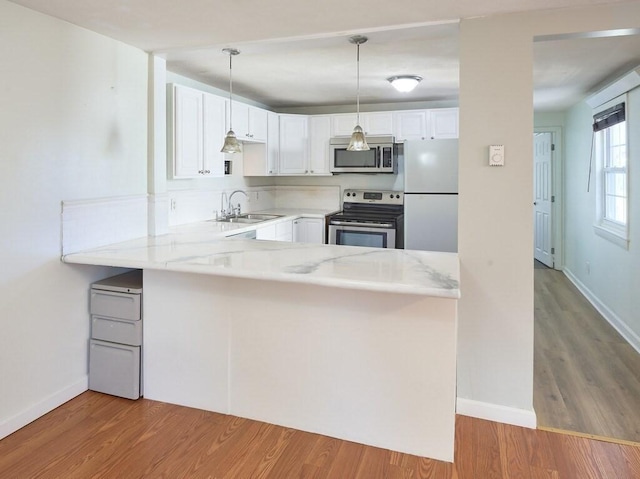 kitchen featuring pendant lighting, appliances with stainless steel finishes, white cabinetry, sink, and kitchen peninsula