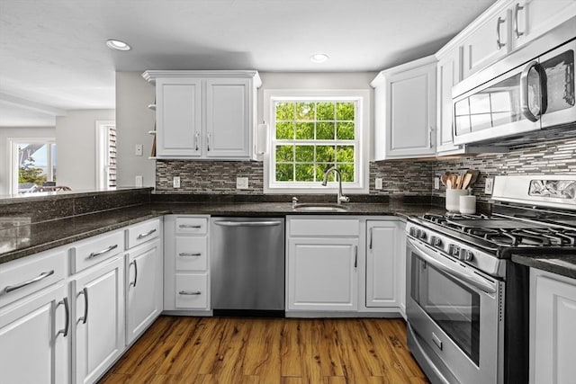 1137 Ferry St, Marshfield, MA 02050 - kitchen with appliances with stainless steel finishes, a sink, white cabinets, dark wood-style flooring, and tasteful backsplash