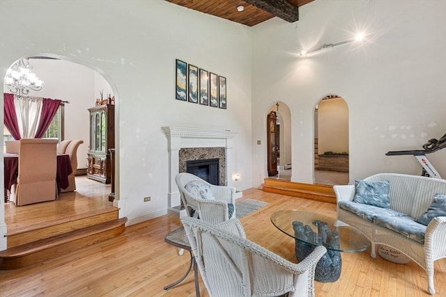 2 Orchard St, Berkley, MA 02779 - living room featuring arched walkways, light wood finished floors, a glass covered fireplace, wooden ceiling with exposed beams, and a high ceiling