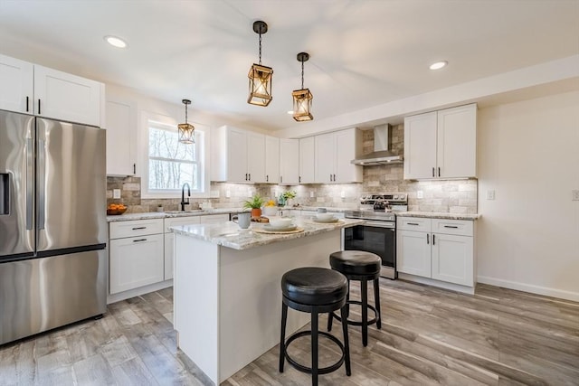 438 Granite St, Worcester, MA 01604 - kitchen with stainless steel appliances, wall chimney exhaust hood, white cabinets, a kitchen island, and a kitchen bar