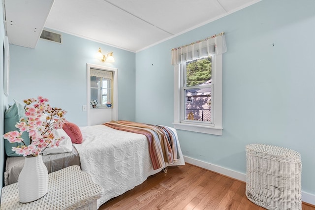 bedroom with hardwood / wood-style flooring and ornamental molding