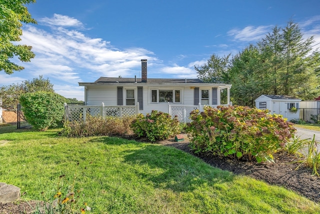 view of front of house with a storage unit and a front lawn