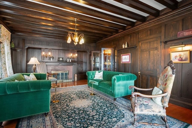living area featuring wooden walls, a glass covered fireplace, a chandelier, and wood finished floors