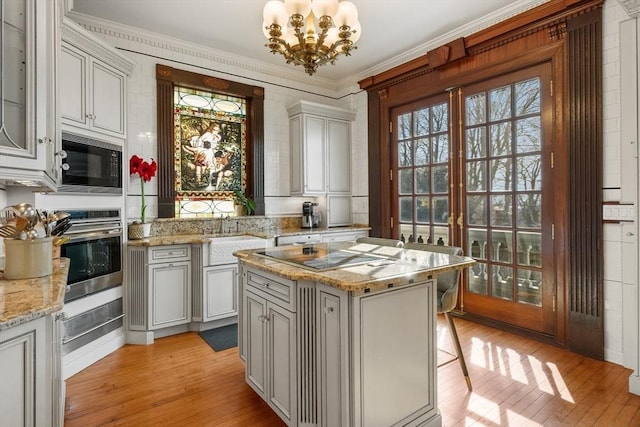 kitchen with a chandelier, plenty of natural light, light wood finished floors, and black appliances