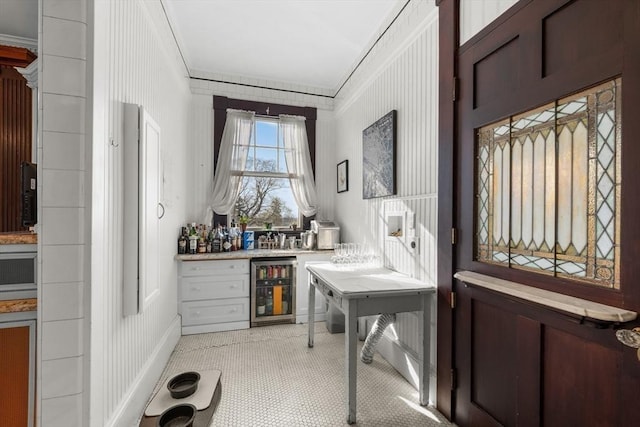 interior space with ornamental molding, a dry bar, and beverage cooler