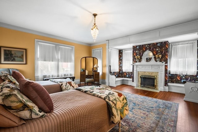 bedroom with baseboards, a fireplace, hardwood / wood-style flooring, and crown molding