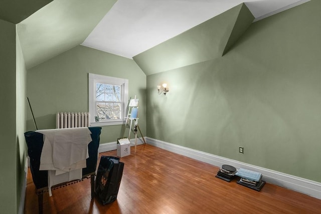 bonus room featuring baseboards, radiator, vaulted ceiling, and wood finished floors