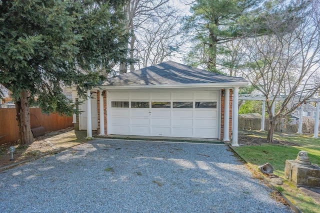 detached garage featuring driveway and fence