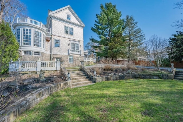 rear view of property featuring a yard and stairs