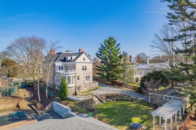 view of front of home with a chimney, a front yard, and a balcony