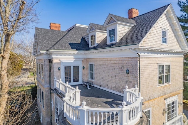 rear view of house with roof with shingles, french doors, and a chimney