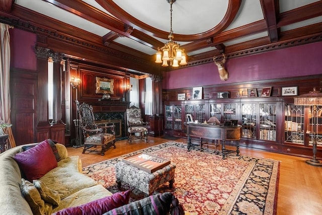 living area with an inviting chandelier, crown molding, beamed ceiling, coffered ceiling, and a premium fireplace