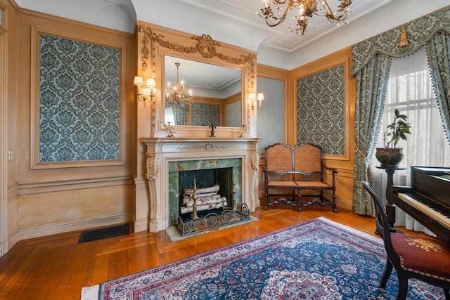 sitting room with visible vents, an inviting chandelier, ornamental molding, a fireplace, and wood finished floors