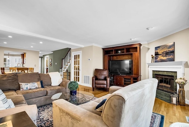 living room featuring light wood-type flooring, a fireplace, and ornamental molding