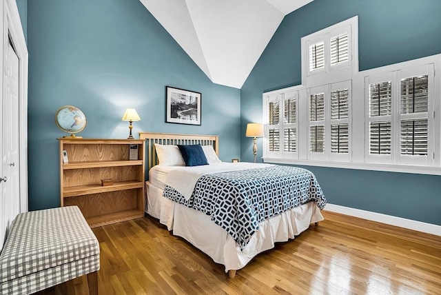 bedroom with a closet, hardwood / wood-style floors, and lofted ceiling