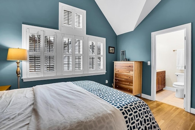 bedroom featuring light hardwood / wood-style floors, multiple windows, and ensuite bath