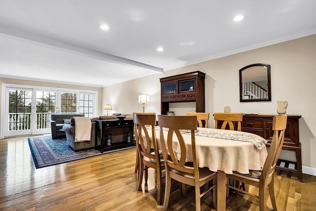 dining space featuring beam ceiling, light wood-type flooring, and crown molding