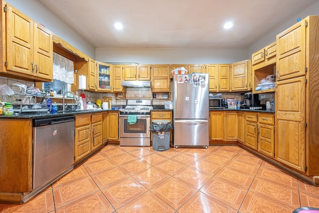 kitchen with tasteful backsplash, dark stone countertops, sink, and appliances with stainless steel finishes