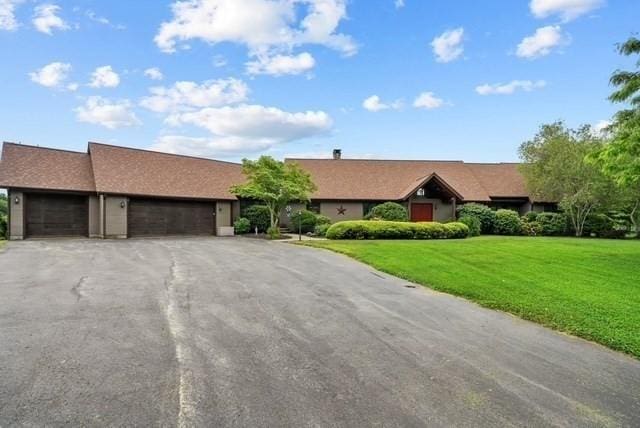 ranch-style home featuring a front lawn, a garage, and aphalt driveway