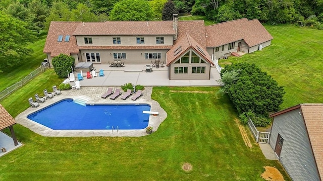 back of property featuring an outdoor pool, fence, a lawn, and a patio area