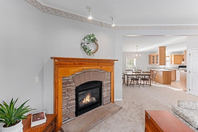 living room featuring crown molding, light carpet, a notable chandelier, and a fireplace