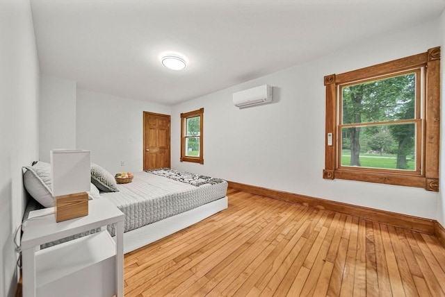 38 Main St, Acton, MA 01720 - bedroom with an AC wall unit, multiple windows, baseboards, and light wood-style flooring