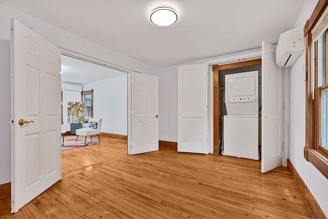 38 Main St, Acton, MA 01720 - unfurnished bedroom featuring estacked washer and dryer, an AC wall unit, light wood finished floors, and baseboards