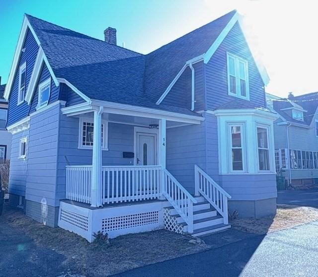 view of front of home with covered porch, a chimney, and roof with shingles