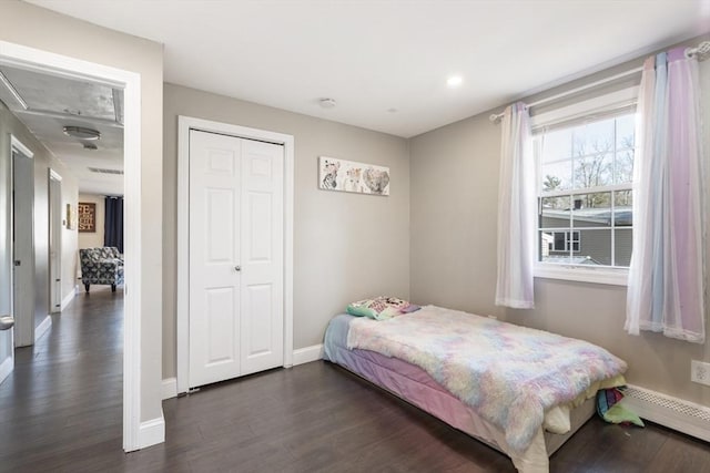 bedroom with a closet, baseboards, dark wood-style flooring, and baseboard heating