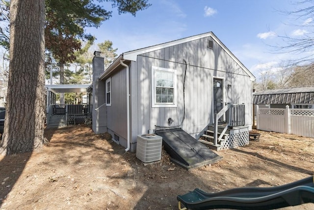 back of house with central AC and a chimney