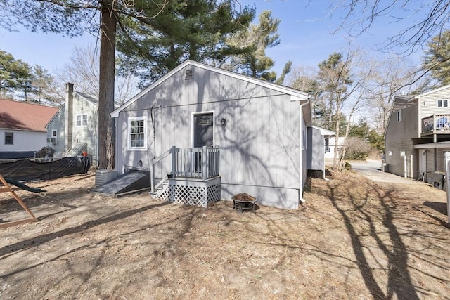 rear view of property featuring fence and a fire pit