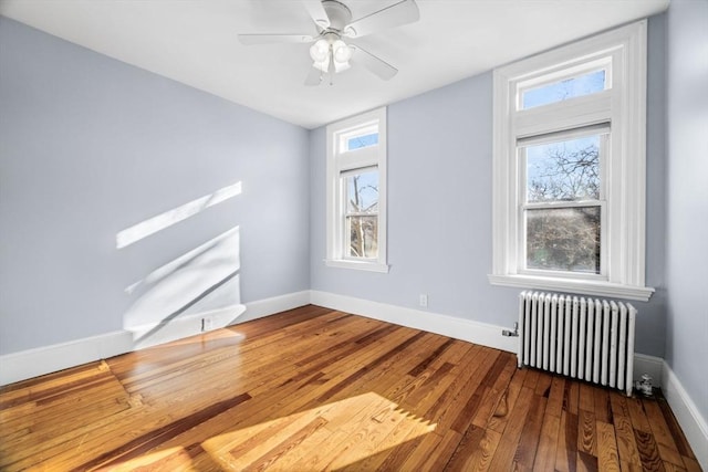 unfurnished room featuring hardwood / wood-style flooring, ceiling fan, and radiator