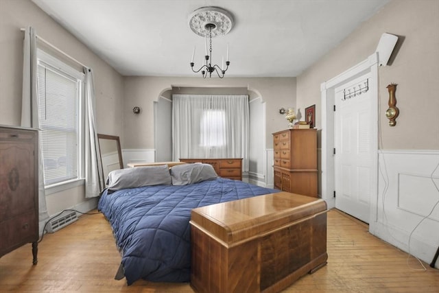 619 Crescent St, Brockton, MA 02302 - bedroom featuring light wood finished floors, arched walkways, multiple windows, a chandelier, and a wainscoted wall