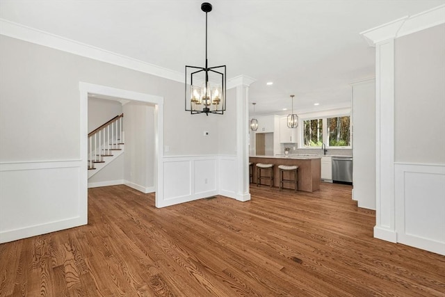 unfurnished dining area with hardwood / wood-style floors, a notable chandelier, and crown molding