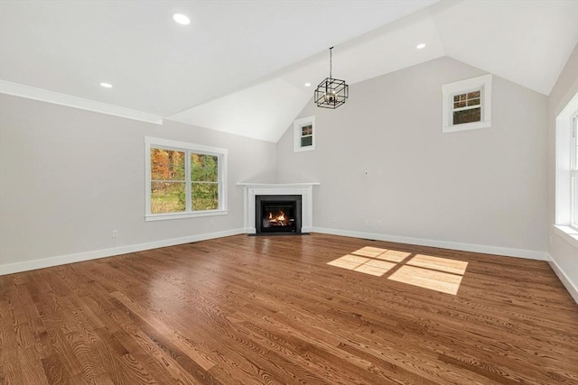 unfurnished living room with wood-type flooring, an inviting chandelier, and lofted ceiling